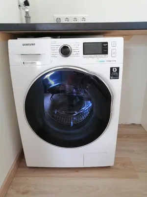 a white washing machine sitting under a counter at Knusse vakantiewoning in Camperduin in Schoorl