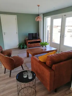 a living room with a couch and a table at Knusse vakantiewoning in Camperduin in Schoorl
