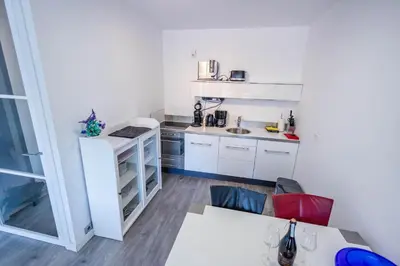a small kitchen with white cabinets and a table at Sterflat 83 in Egmond aan Zee