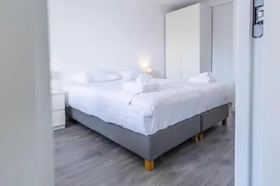 a bedroom with a large bed with a mirror at Sterflat 83 in Egmond aan Zee