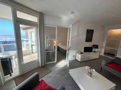 a living room with a couch and a table with a laptop at Sterflat 83 in Egmond aan Zee