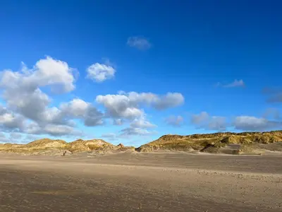 a sandy beach with mountains in the background at Vakantiehuis aan Zee (100 meter van het strand) in Egmond aan Zee