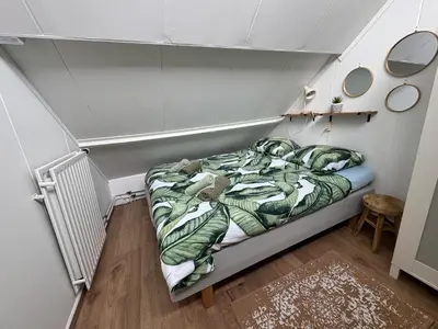 a small bedroom with a bed in a room at Vakantiehuis aan Zee (100 meter van het strand) in Egmond aan Zee
