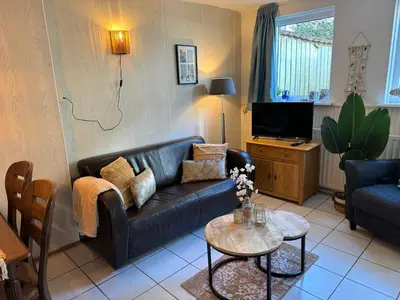 a living room with a leather couch and a table at Vakantiehuis aan Zee (100 meter van het strand) in Egmond aan Zee
