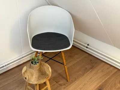 a white chair sitting in a room with a potted plant at Vakantiehuis aan Zee (100 meter van het strand) in Egmond aan Zee