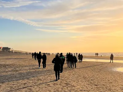 a group of people walking on the beach at Vakantiehuis aan Zee (100 meter van het strand) in Egmond aan Zee