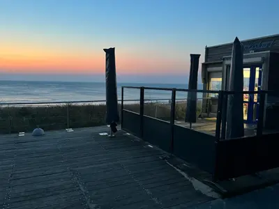 a house with a deck with a view of the ocean at Vakantiehuis aan Zee (100 meter van het strand) in Egmond aan Zee