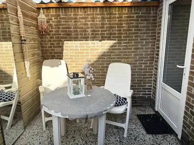 a table and chairs on a patio with a brick wall at Vakantiehuis aan Zee (100 meter van het strand) in Egmond aan Zee