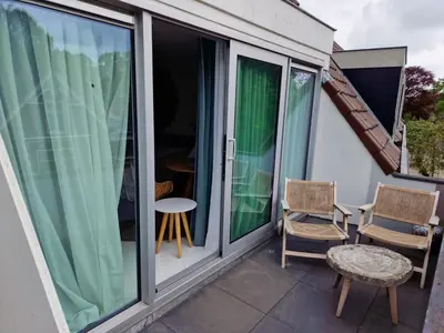 a balcony with sliding glass doors and a table and chairs at Hotel Liberte in Schoorl