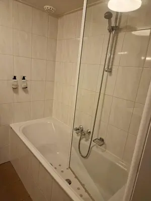 a bathroom with a tub and a shower with a glass door at Hotel Liberte in Schoorl