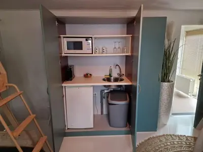 a small kitchen with a sink and a microwave at Hotel Liberte in Schoorl