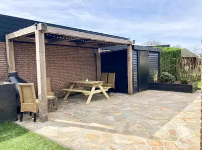 a patio with a wooden table and a wooden pergola at NEW: Summerhouse near beach&lake in Noordwijkerhout