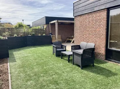 a patio with chairs and a table on grass at NEW: Summerhouse near beach&lake in Noordwijkerhout