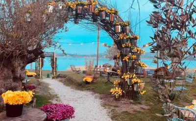 a garden with an arch with flowers and tables at NEW: Summerhouse near beach&lake in Noordwijkerhout