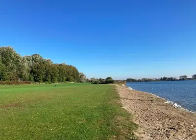 a grassy field next to a body of water at NEW: Summerhouse near beach&lake in Noordwijkerhout