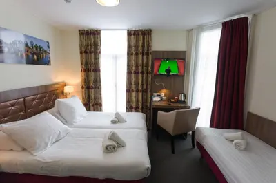 a hotel room with two beds and a desk at Hotel Park Plantage in Amsterdam