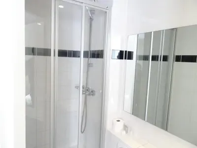 a white bathroom with a shower and a mirror at Hotel Park Plantage in Amsterdam