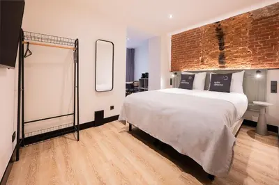 a bedroom with a large bed and a brick wall at Limehome Amsterdam Leidsekruisstraat in Amsterdam
