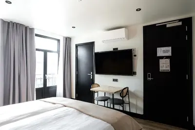 a bedroom with a bed and a table and a tv at Limehome Amsterdam Leidsekruisstraat in Amsterdam