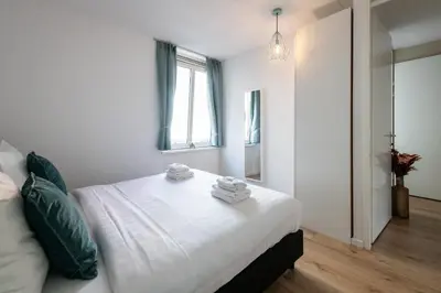 a bedroom with a bed with white sheets and a window at Aparthotel North Spacious Suite for 6 Guests in Amsterdam