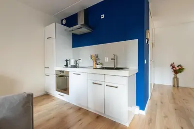 a kitchen with white cabinets and a blue wall at Aparthotel North Spacious Suite for 6 Guests in Amsterdam