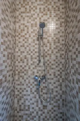 a shower in a bathroom with brown and white tiles at Aparthotel North Spacious Studio for two in Amsterdam