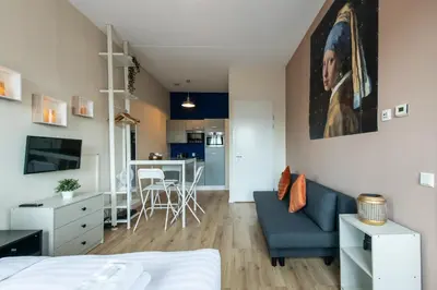 a living room with a blue couch and a kitchen at Aparthotel North Spacious Studio for two in Amsterdam