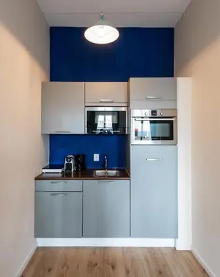 a kitchen with white cabinets and a blue wall at Aparthotel North Spacious Studio for two in Amsterdam