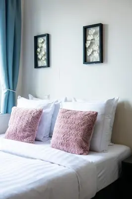 a white bed with two pink pillows on it at Aparthotel North Spacious Studio for two in Amsterdam