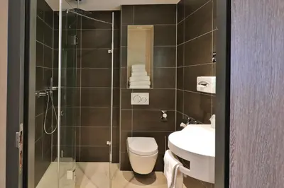 a bathroom with a shower and a toilet and a sink at XO Hotel Inner in Amsterdam