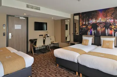 a hotel room with two beds and a dining area at XO Hotel Inner in Amsterdam