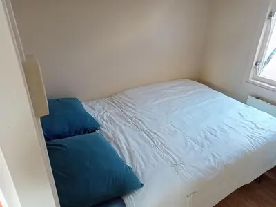 a small bedroom with a bed with blue pillows at tiny house nabij de kust in Dirkshorn