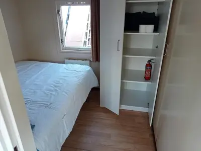 a small bedroom with a bed and a window at tiny house nabij de kust in Dirkshorn