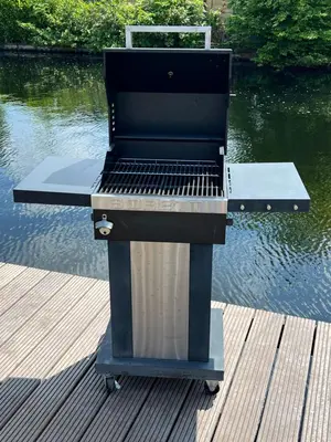 a barbecue grill sitting on a dock next to the water at NEW - Waterhouse Linada on a lake near Amsterdam in Vinkeveen