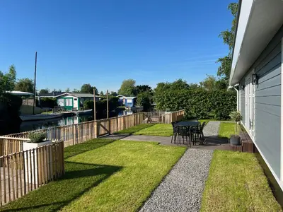 a backyard with a table and a fence at NEW - Waterhouse Linada on a lake near Amsterdam in Vinkeveen