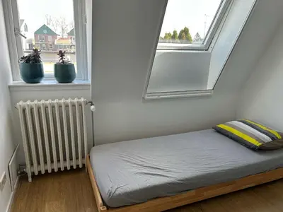 a small bed in a room with two windows at Luxurious Family Home Amstelveen in Amstelveen
