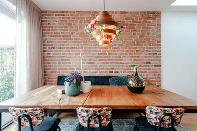 a dining room table with chairs and a brick wall at Luxurious Family Home Amstelveen in Amstelveen