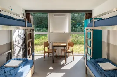 a room with bunk beds and a table and chairs at Stayokay Hostel Haarlem in Haarlem
