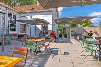 a patio with tables and chairs and umbrellas at Stayokay Hostel Haarlem in Haarlem