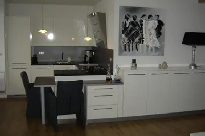 a kitchen with white cabinets and a table with chairs at Sterflat 87 in Egmond aan Zee