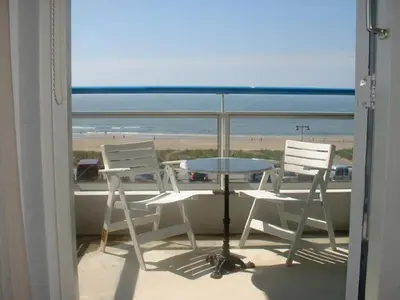 a balcony with a table and chairs and the beach at Sterflat 87 in Egmond aan Zee