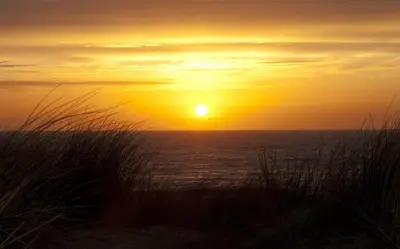 a sunset on the beach with the ocean at Sterflat 97 in Egmond aan Zee
