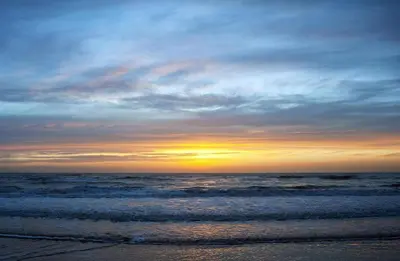 a sunset on a beach with the ocean at Sterflat 97 in Egmond aan Zee
