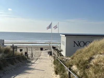 two flags on a beach next to a building at Sterflat 97 in Egmond aan Zee