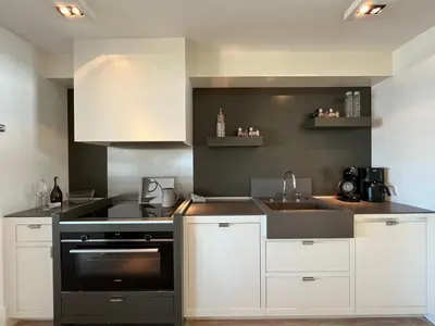 a kitchen with white cabinets and a black oven at Sterflat 97 in Egmond aan Zee