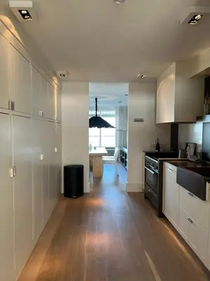 a kitchen with white cabinets and a wooden floor at Sterflat 97 in Egmond aan Zee