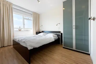 a bedroom with a bed and a large window at Sterflat 99 in Egmond aan Zee