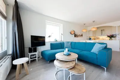 a living room with a blue couch and a table at Sterflat 99 in Egmond aan Zee