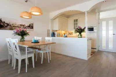 a kitchen with a wooden table and white cabinets at Sterflat 99 in Egmond aan Zee