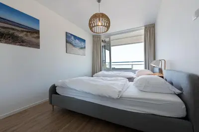 a bedroom with a bed and a large window at Sterflat 99 in Egmond aan Zee